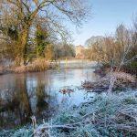 Frost covered banks ot the River Meon with St Mary and All Saints Church in the distance
